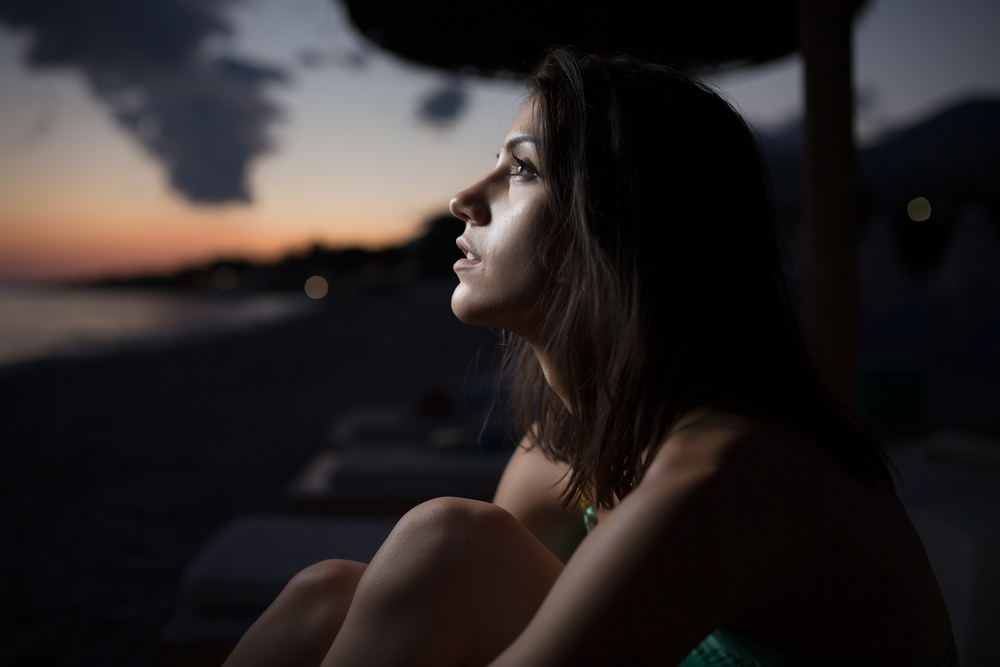 Woman watching the ocean,sea horizon with a Moon on the sky.Eclipse of the Moon.Eclipse of the sun.Stargazing,watching stars on the beach under the moonlight.Enjoying summer nights.Night sky.Sunrise