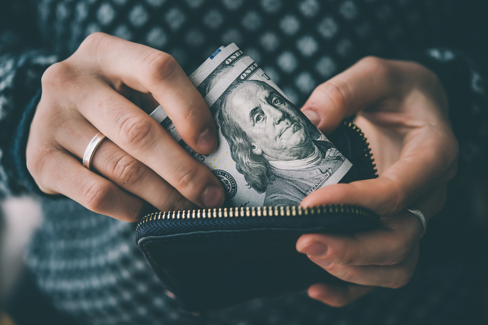 Hands holding us dollar bills and small money pouch. Toned picture