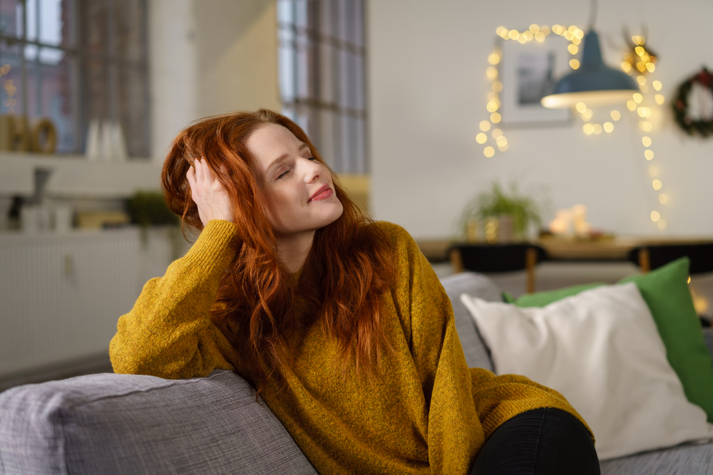 redhead woman sitting at home in winter holidays leaning her head on her hand