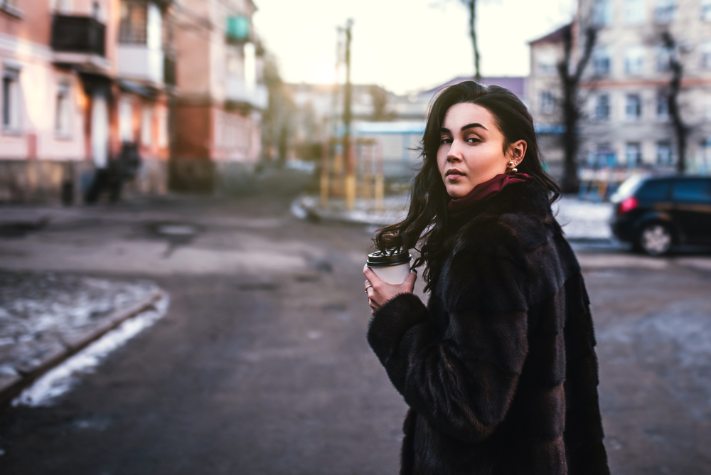 Long hair brunette girl walking on the street with cup of coffee