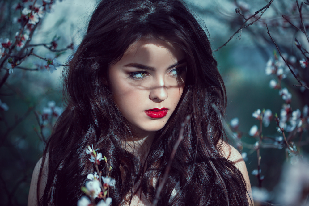 Fashion Art Mystical Spring Model Girl Portrait in Moonlight Night. Sexy Glamour Summer Beautiful Woman with Healthy and Beauty Brown Hair with flowers over nature blurred background. Fairy