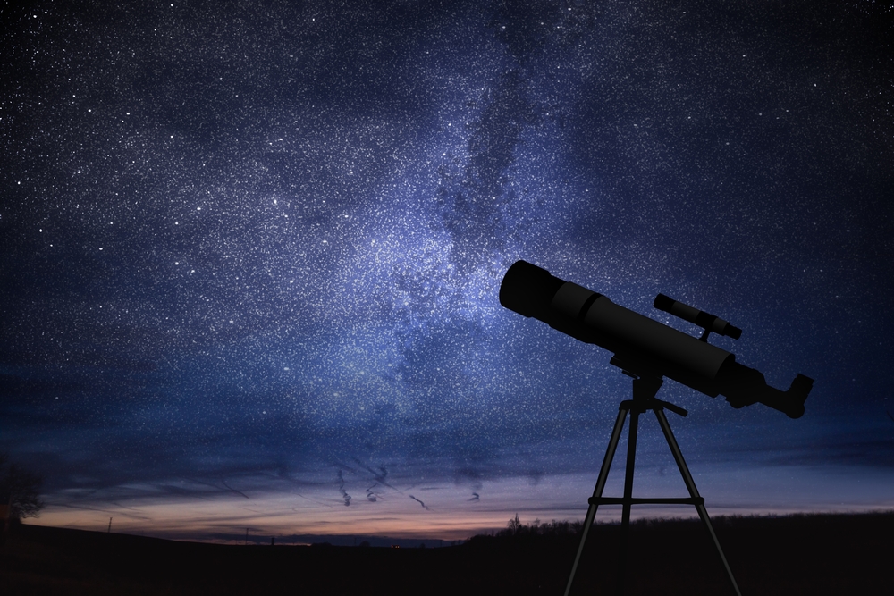 Silhouette of telescope and starry night sky in background. Astronomy and stars observing concept