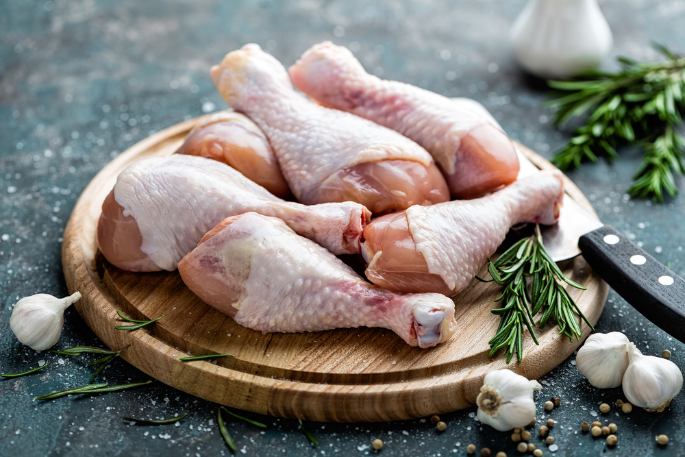 Raw uncooked chicken legs, drumsticks on wooden board, meat with ingredients for cooking