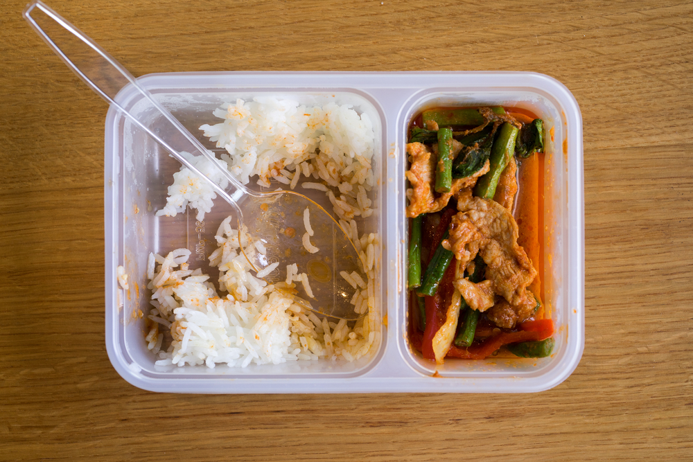 Leftover Thai food rice with Stir fried pork belly and red curry paste with stringbean in a plastic box, on top view.
