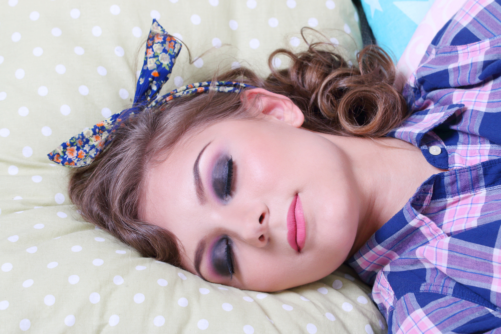 girl in checkered shirt sleeps on soft pillows in studio