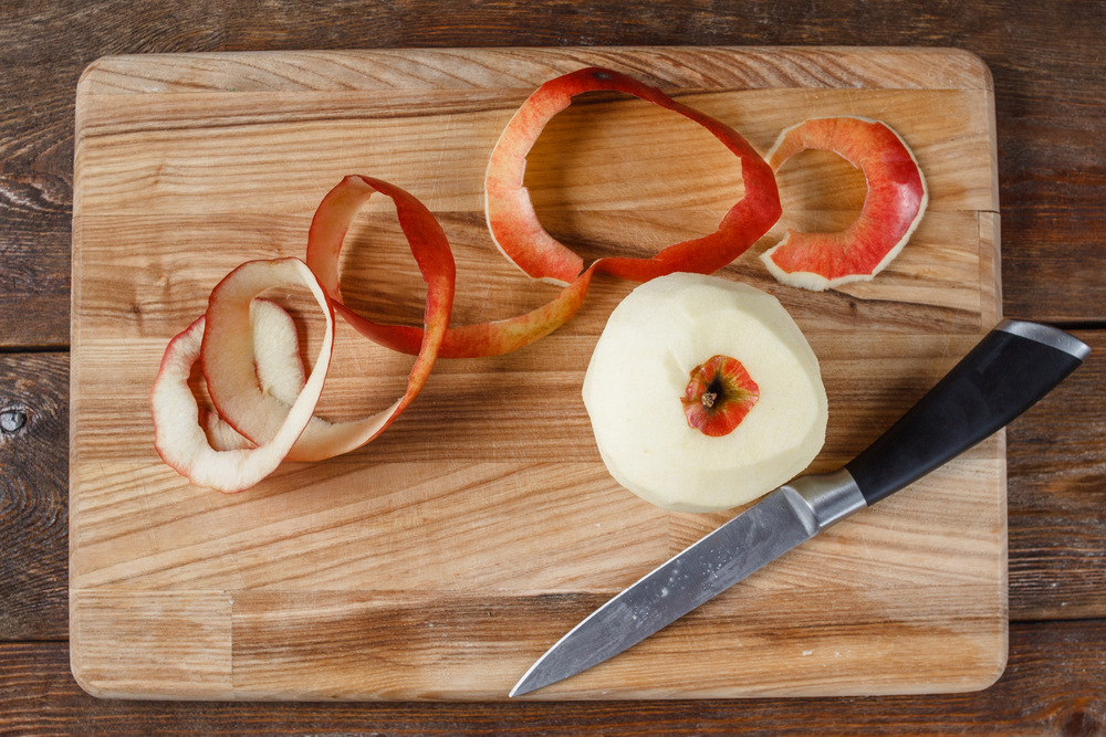 Top view of single red apple paring by knife. Fresh fruit lay on wooden desk. Healthy food, dietary, cooking concept