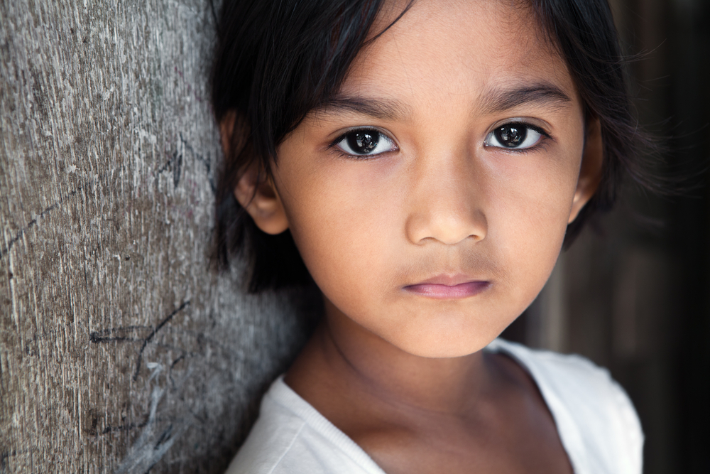 Portrait of a pretty 8 year old Filipina girl in poverty-stricken neighborhood, natural light.
