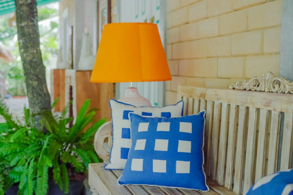 A lamp rests on pillows of blue and white.
