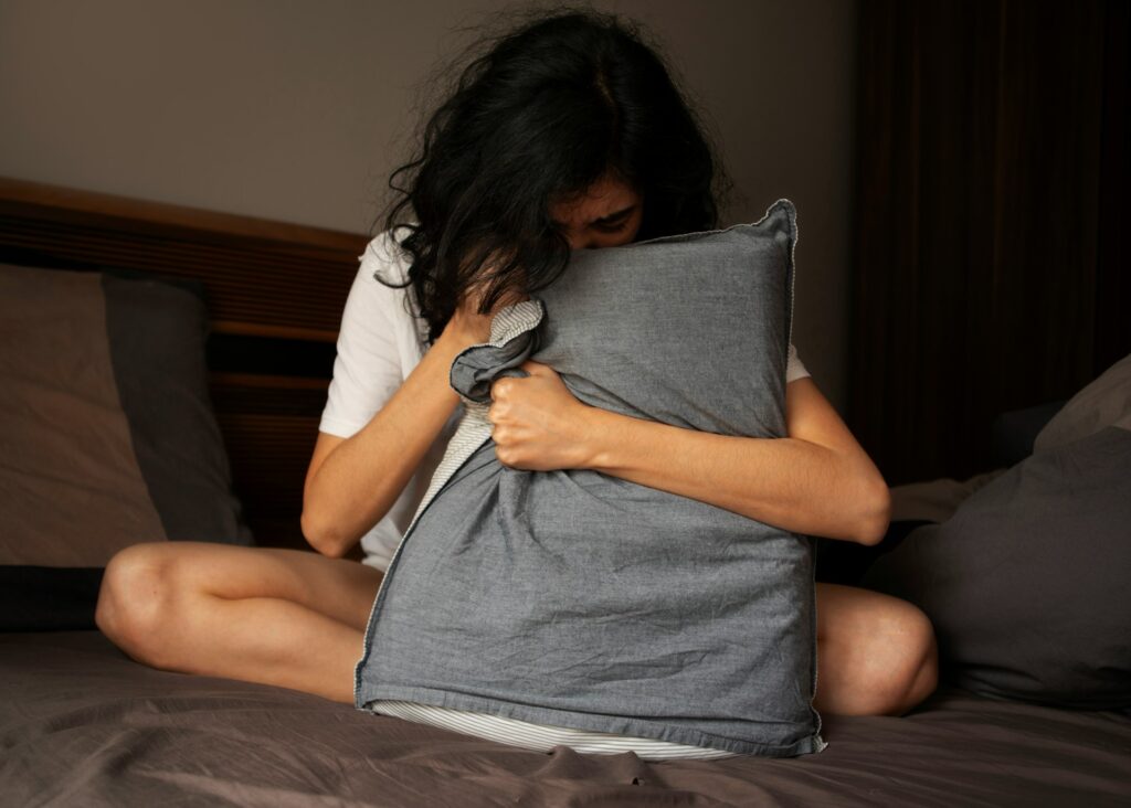 A woman sitting on a bed holding a pillow
