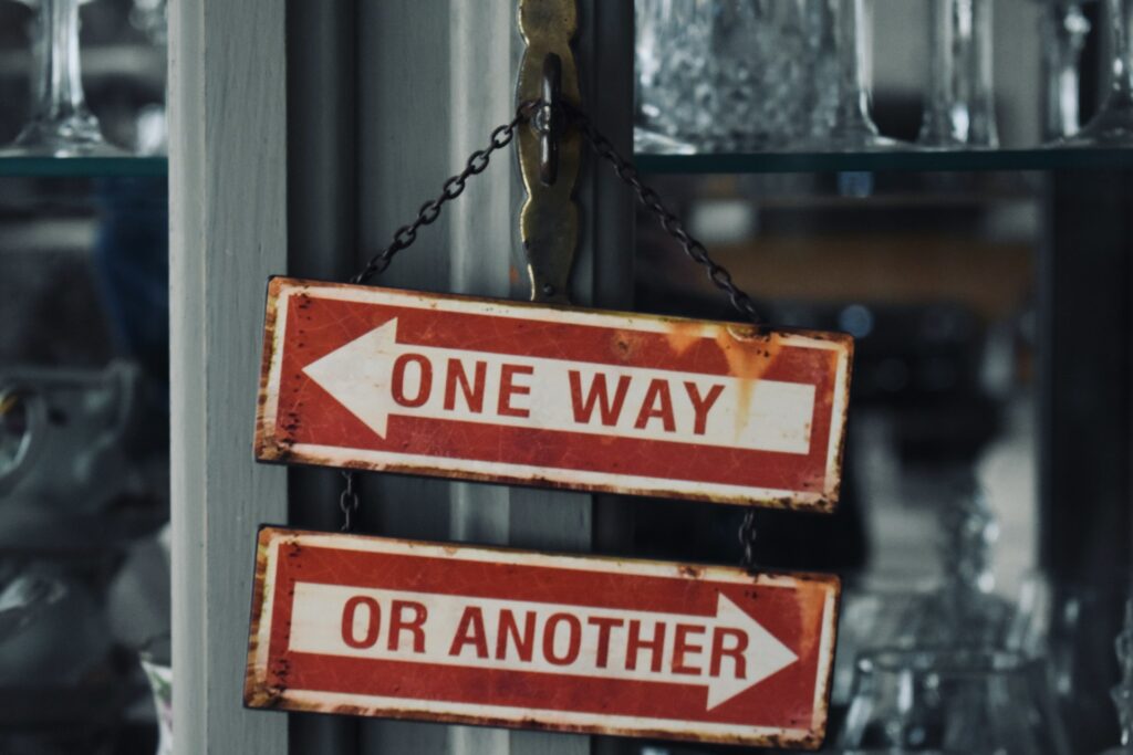 two red and white signs hanging from a metal pole
