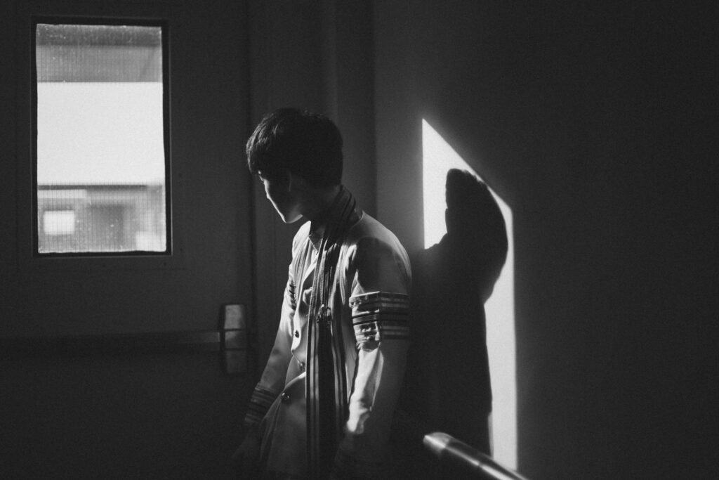 grayscale photography of man standing beside door
