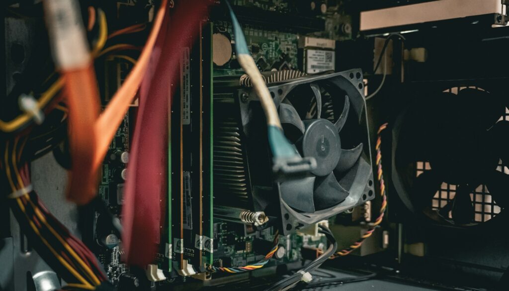 A close up of a computer with a fan and wires
