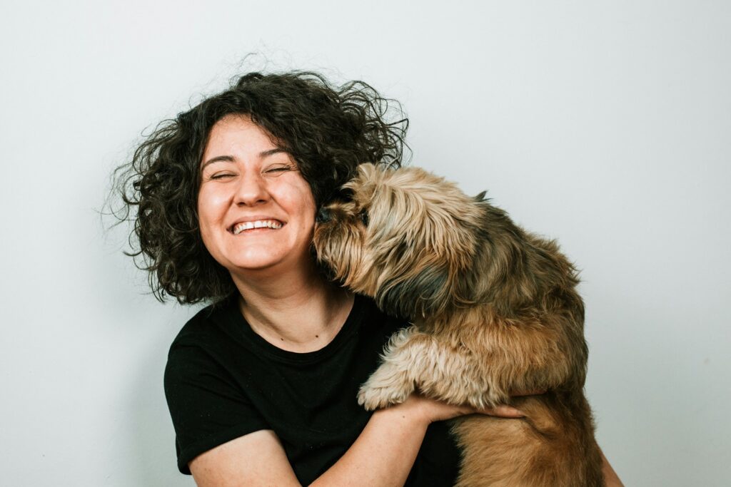 dog kissing woman in black crew-neck shirt
