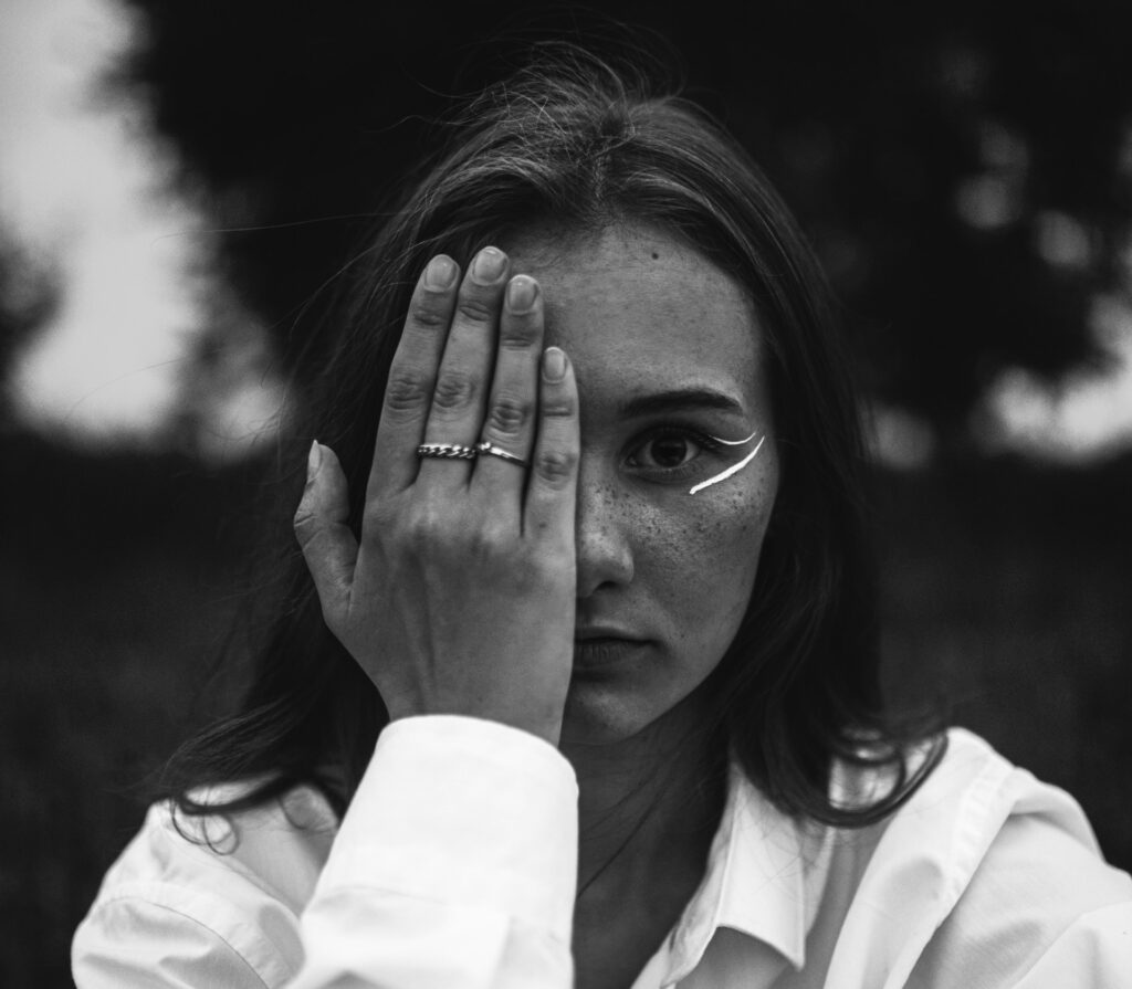 a black and white photo of a woman holding her hands to her face
