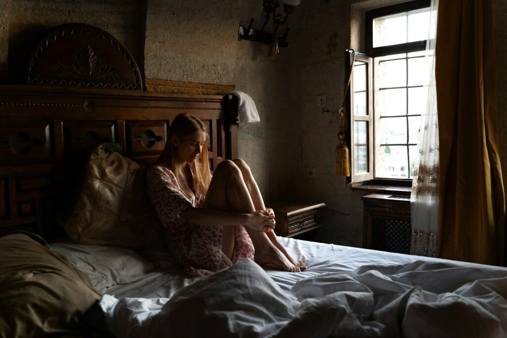 grayscale photography person reading book on top of bed