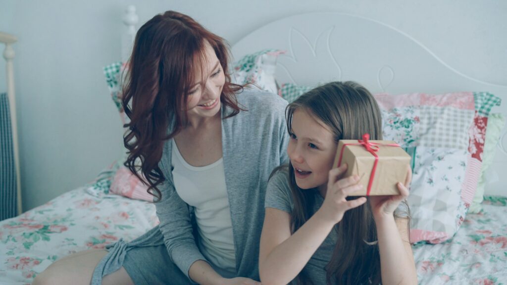 Mother gives her daughter a wrapped present.

