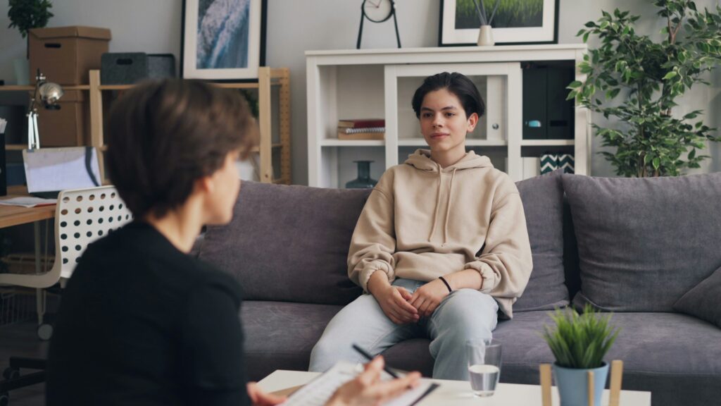 a woman sitting on a couch talking to another woman
