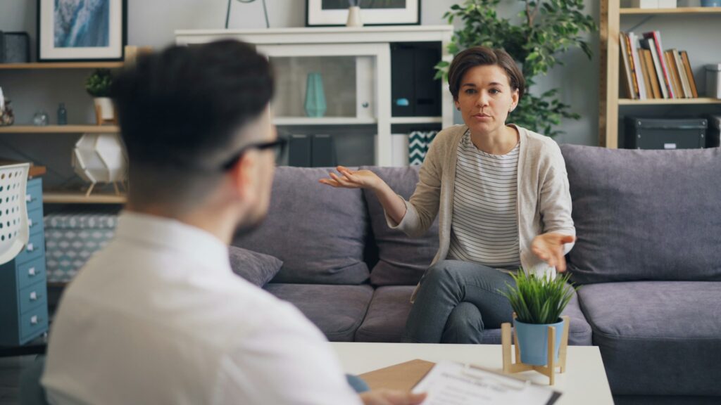 a woman sitting on a couch talking to a man
