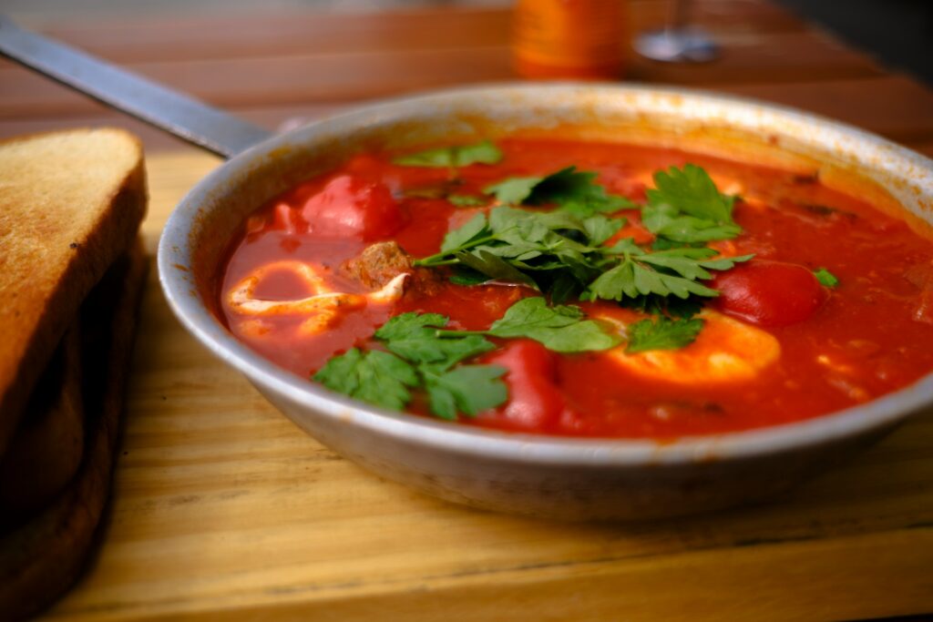 a bowl of tomato soup with bread on the side
