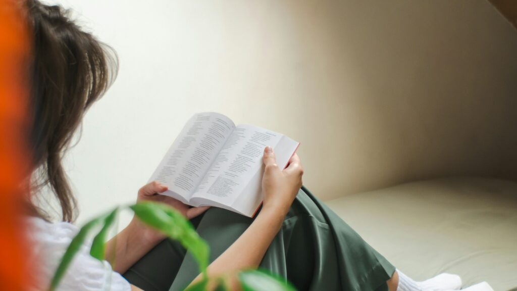 a woman sitting on a couch reading a book
