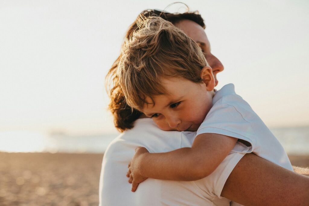 boy hugging woman during daytime
