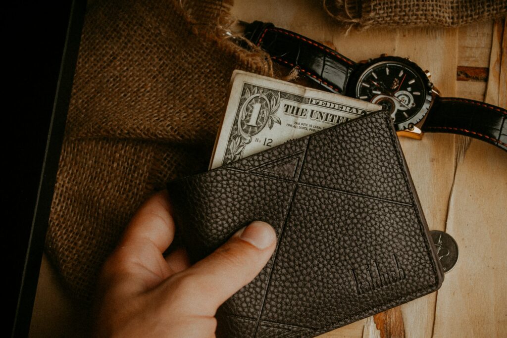 a person is holding a wallet and a watch
