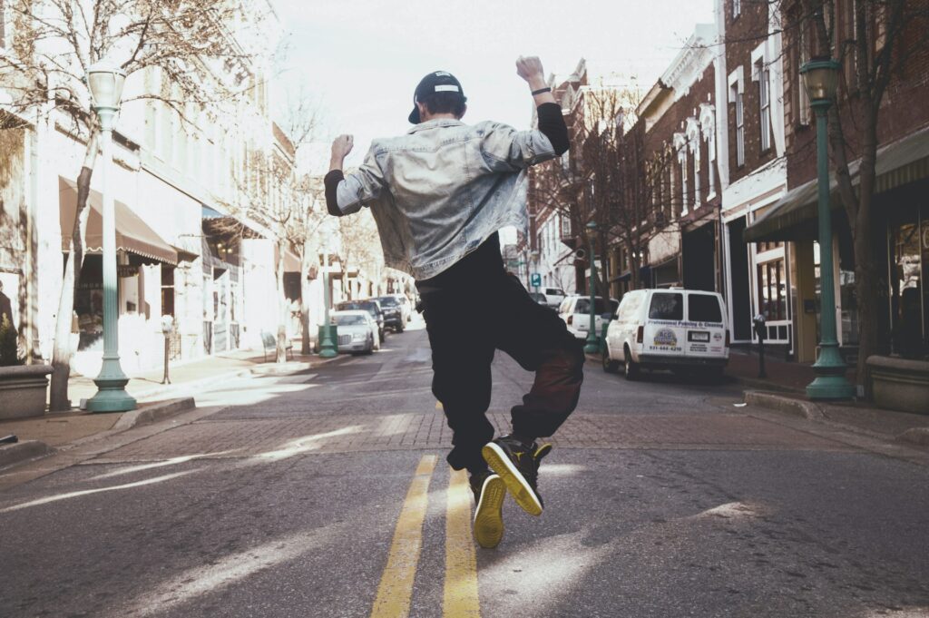 man jumping on the middle of the street during daytime

