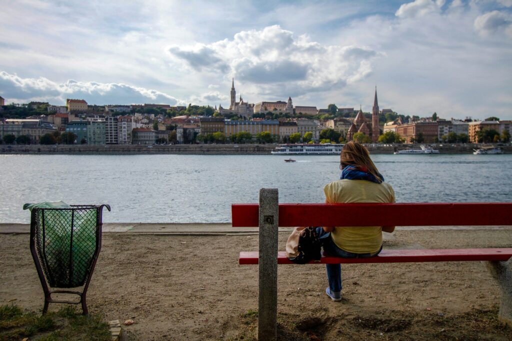 a woman sitting on a red bench next to a body of water
