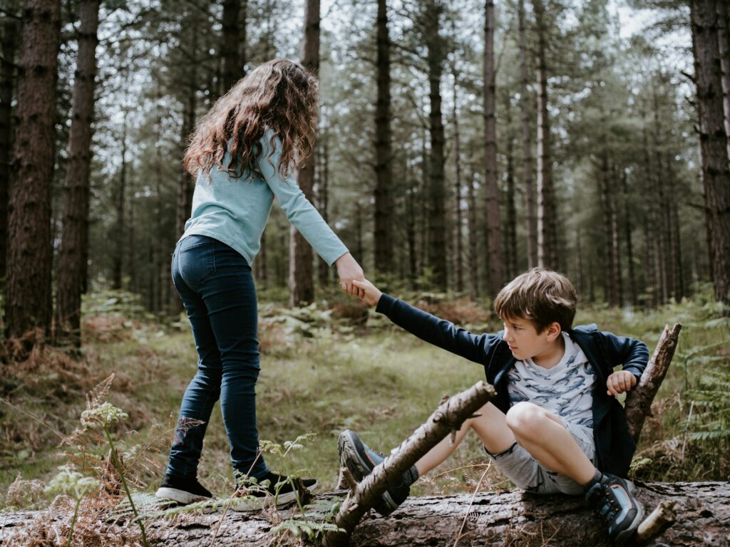 boy and girl playing on three tree log
