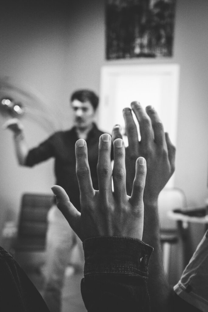 grayscale photography of two people raising their hands
