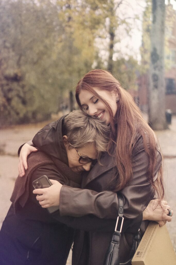 two women hugging each other on a city street
