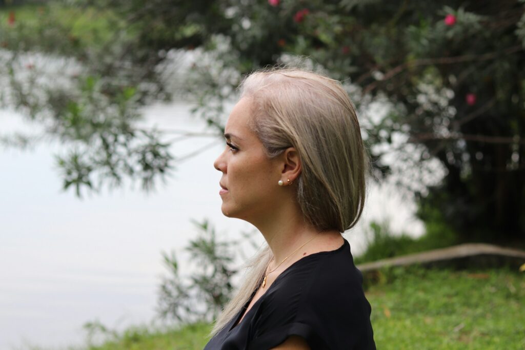 a woman with blonde hair standing in front of a body of water
