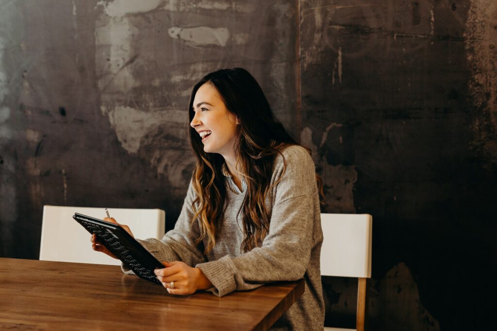 woman sitting around table holding tablet

