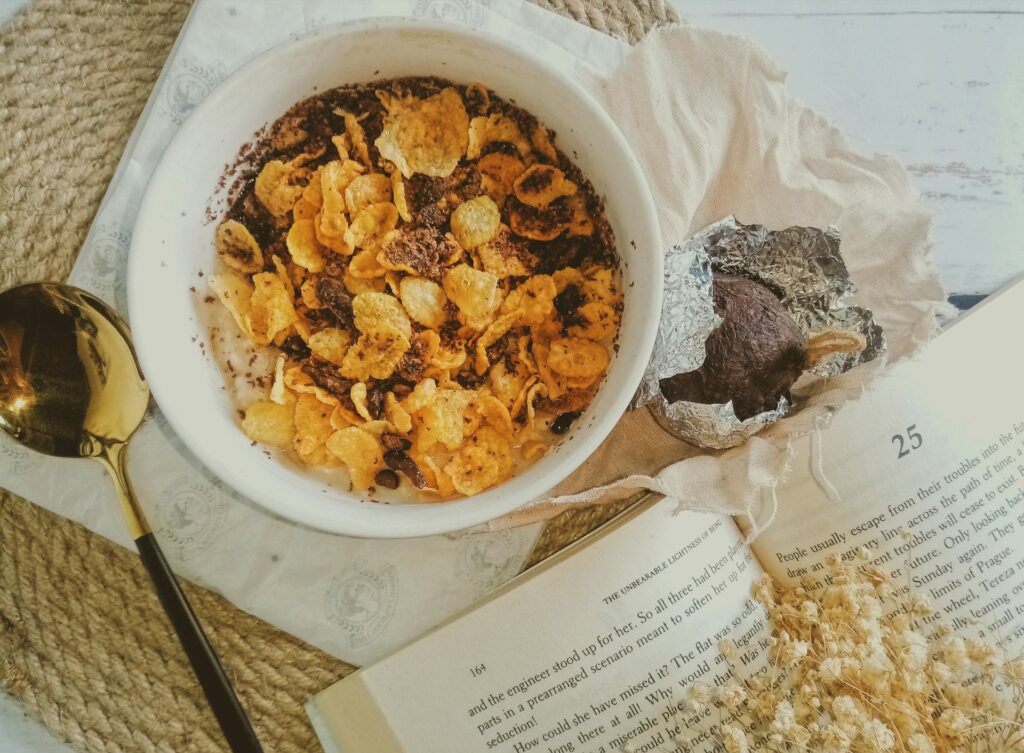a bowl of cereal next to an open book
