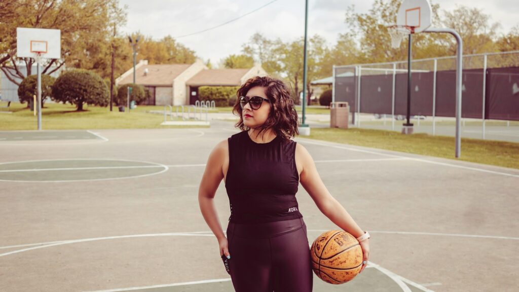 woman standing outdoors holding basketball
