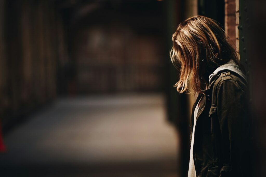 woman leaning against a wall in dim hallway
