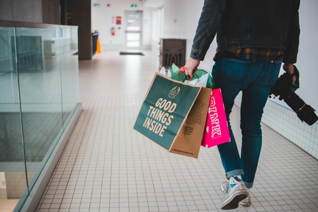person walking while carrying a camera and paper bags

