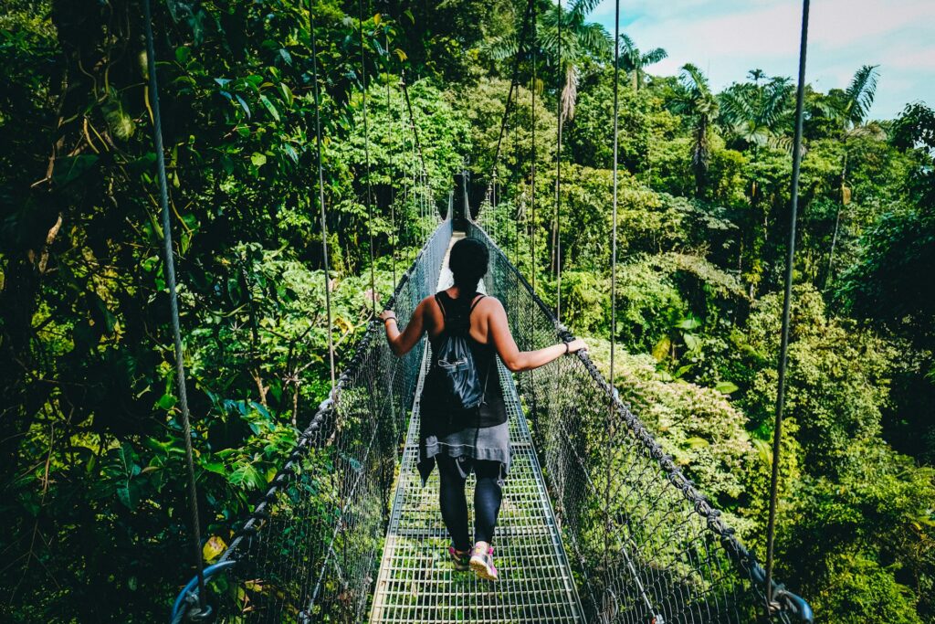 woman in black shirt and black pants standing on hanging bridge
