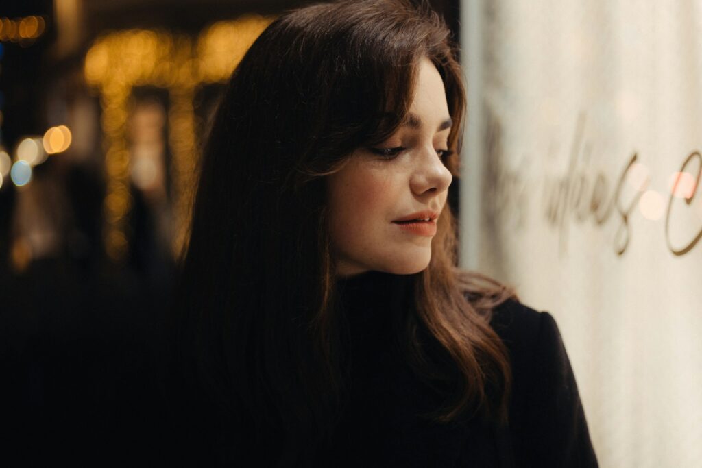 a woman standing in front of a wall with her eyes closed
