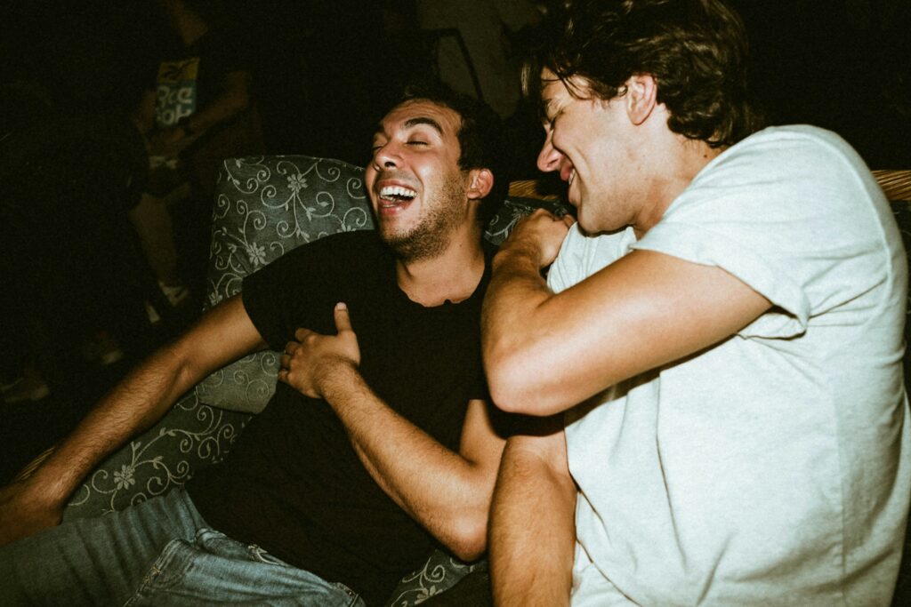 man in white tank top beside man in black crew neck t-shirt
