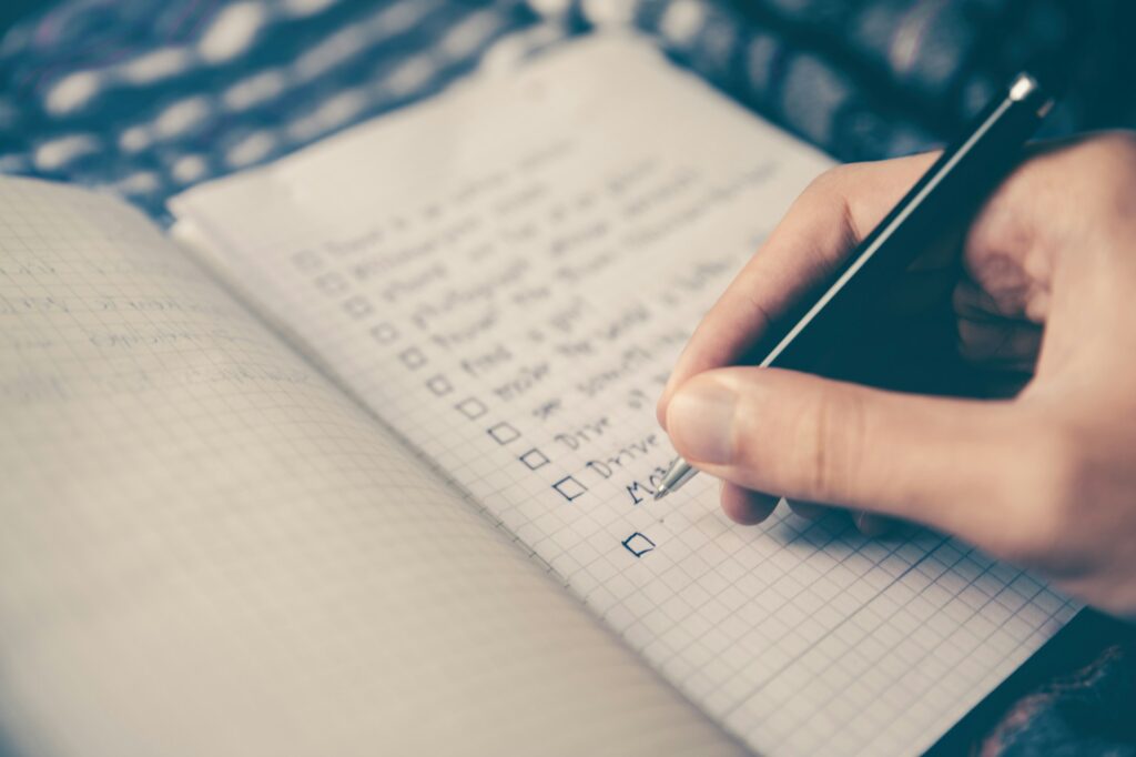 person writing bucket list on book
