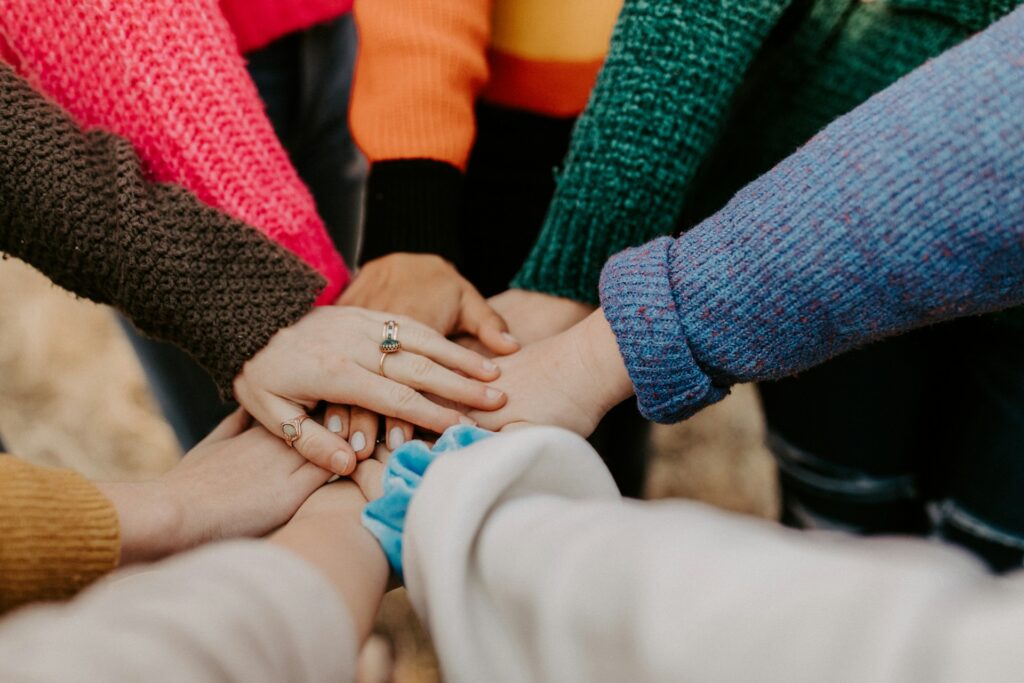 person in red sweater holding babys hand
