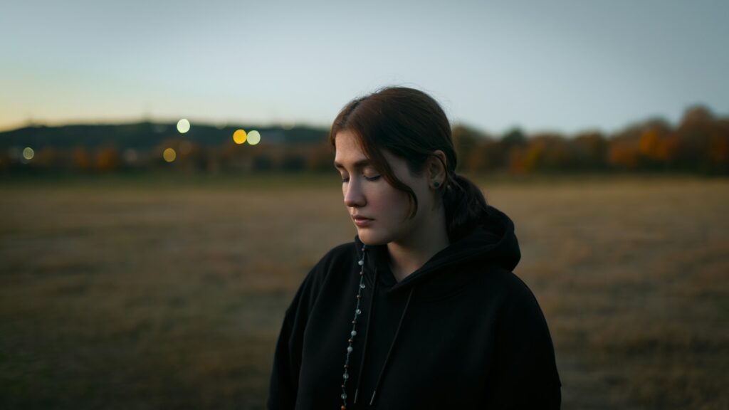 A woman standing in a field at sunset
