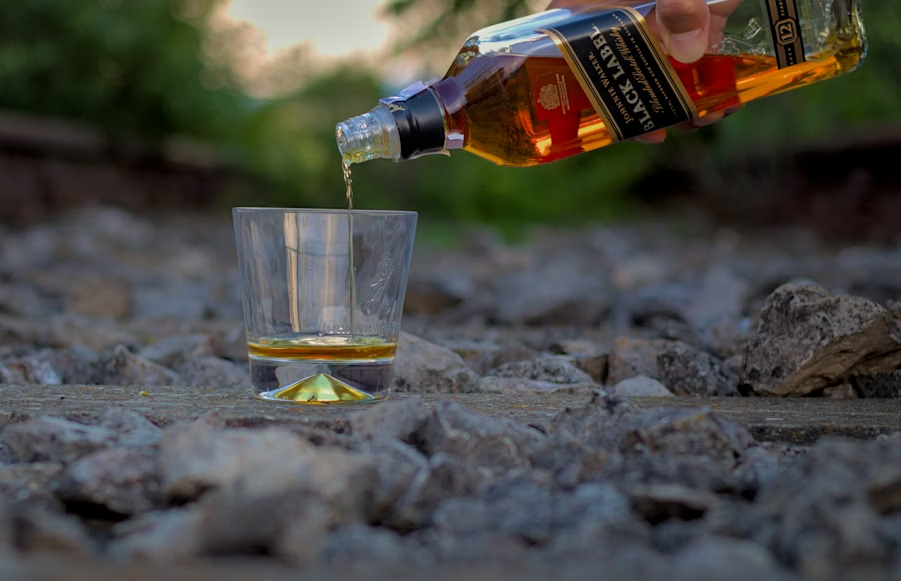 bottle of liquor poured into a glass, image