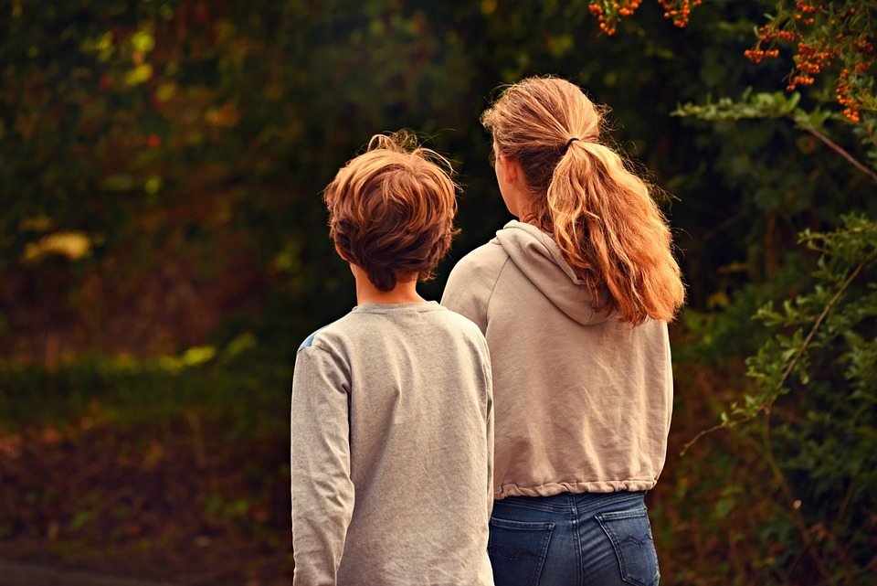 two siblings near a pond