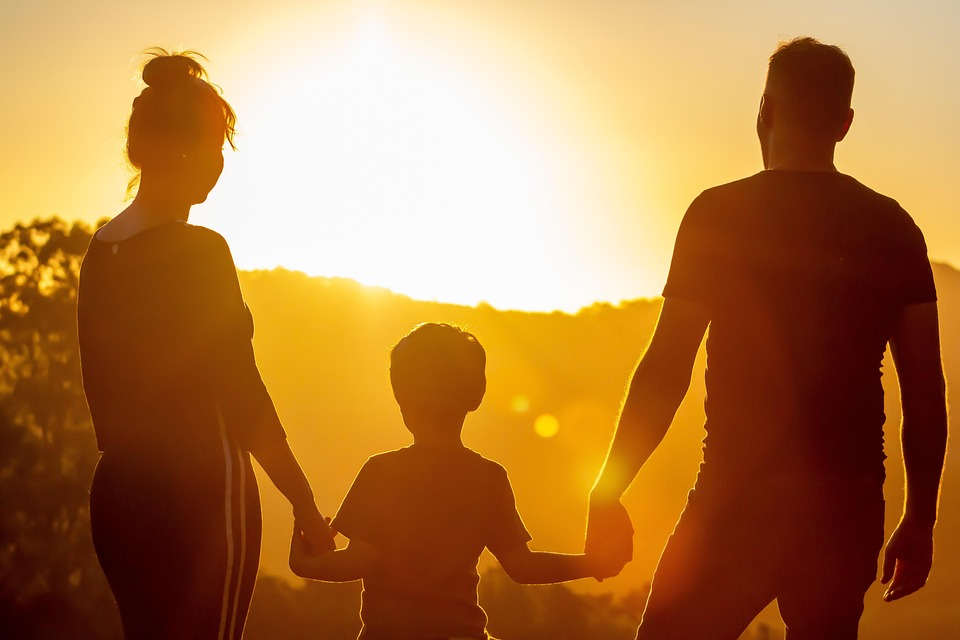 parents and child staring into the sunset, image