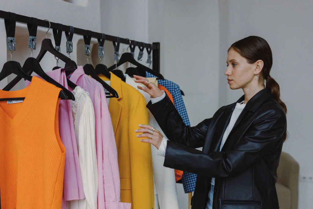 Woman in Black Leather Jacket Standing Near Clothing Rack
