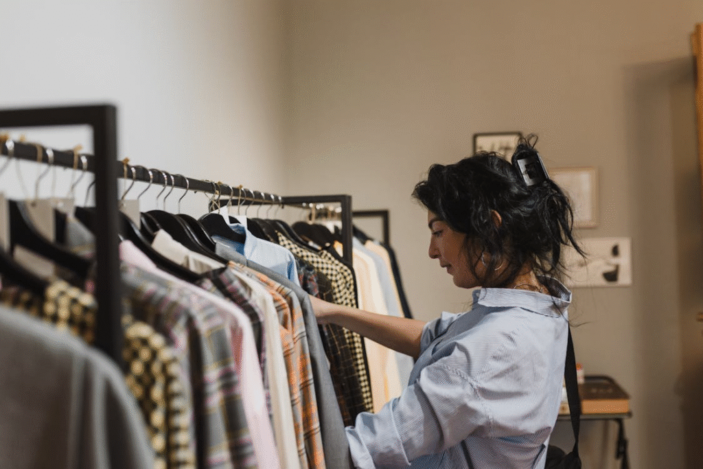 Woman in White Shirt Standing Near Clothes Rack
