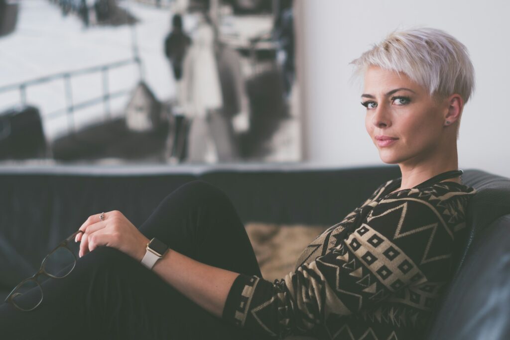 woman sitting on sofa holding eyeglasses
