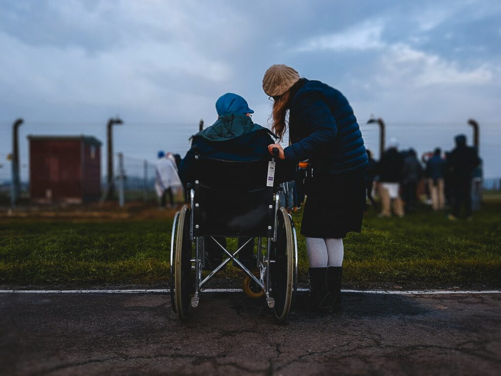 woman standing near person in wheelchair near green grass field
